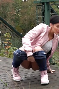 Black Haired Doll Squats To Piss On Decking